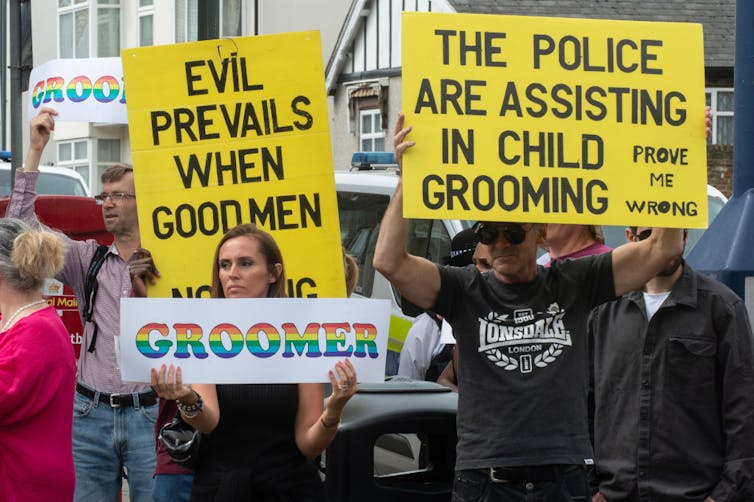 Group of protesters hold signs with text reading 'groomer.'
