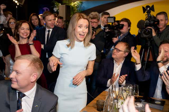 Estonian Prime Minister Kaja Kallas looks jubilant while surrounded by supporters and cameras