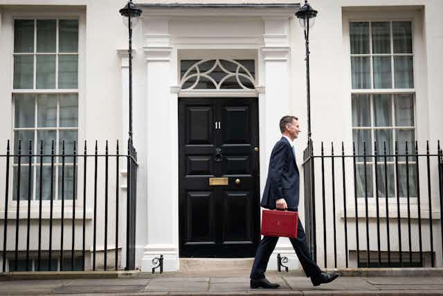 Jeremy Hunt walking past 11 Downing Street with his red ministerial box in hand.