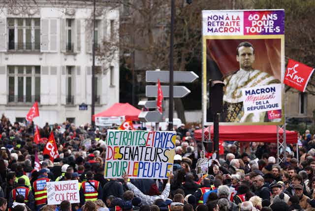 Un manifestant tient une banderole sur laquelle on peut lire "Retraites des sénateurs et salaires pour le peuple" lors d'une manifestation à l'occasion de la huitième journée de grèves et de protestations à travers le pays contre la réforme des retraites proposée par le gouvernement, à Paris, le 15 mars 2023.