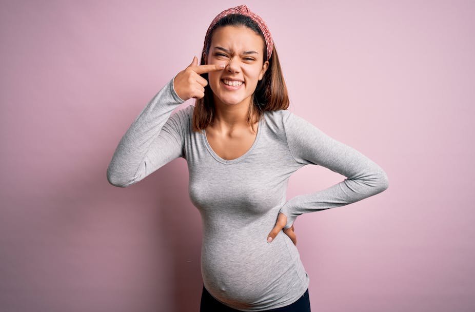 Une femme enceinte montre son nez en souriant/grimaçant.