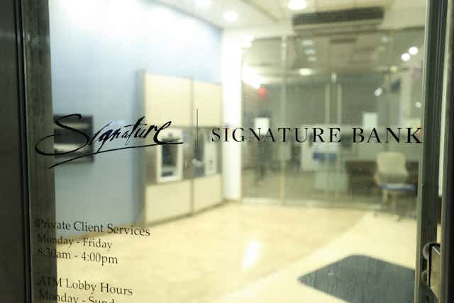 Closed glass doors show the Signature Bank logo. ATM machines and the bank's lobby appear in the background.