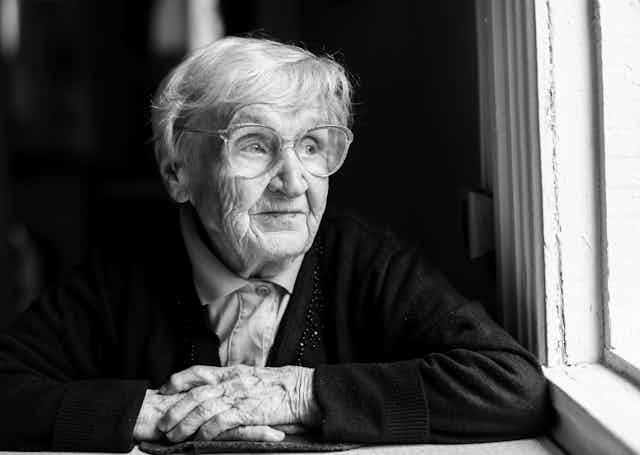 A woman with gray hair looking out a window