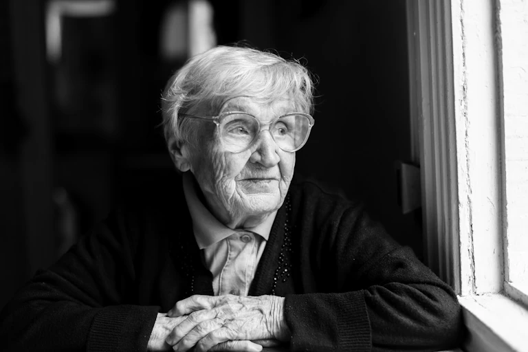A woman with gray hair looking out a window