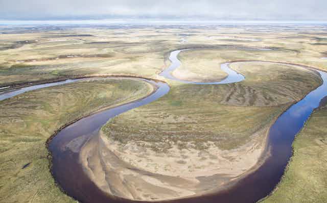 A river meanders through an wide open landscape of grasslands