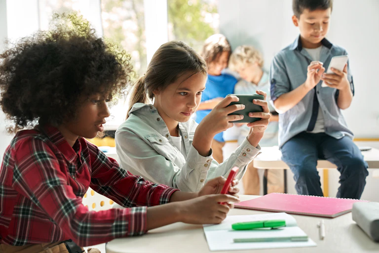 niños utilizando sus teléfonos móviles en el aula.