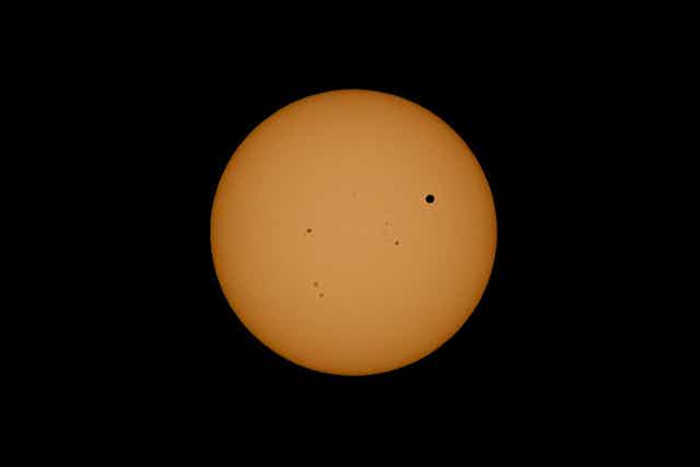 Disco solar con algunas manchas y el disco de Venus encima como una mancha negra muy destacada
