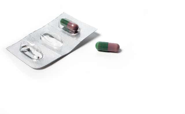 Plaquette de médicaments ouverte, avec une gélule oubliée à côté.
