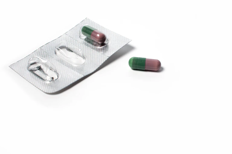 Plaquette de médicaments ouverte, avec une gélule oubliée à côté.