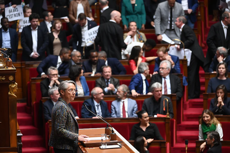 Les membres du Parlement de la coalition de gauche NUPES (Nouvelle Union Populaire Ecologique et Sociale) tiennent des pancartes avant le début du discours du Premier ministre français Elisabeth Borne (G), avant qu'elle ne confirme l'adoption de la loi sur les retraites sans vote du Parlement lors d'une session sur la réforme des retraites du gouvernement à la chambre basse de l'Assemblée nationale, à Paris le 16 mars 2023.
