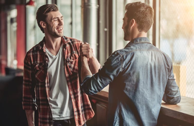 Two young men greet each other.