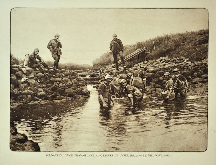 Soldiers in flooded field with sandbags