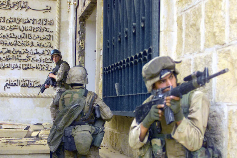 Three men in helmets and khaki carrying guns.