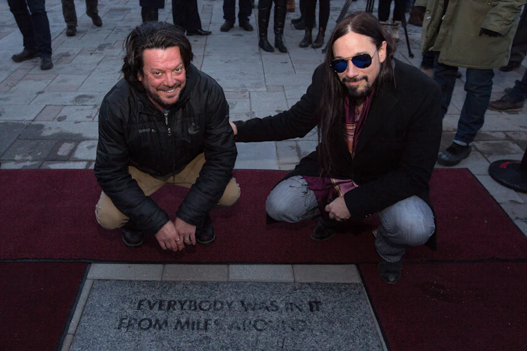 Two men seen kneeling at a plaque.