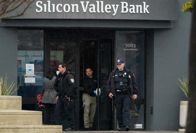 Two police officers exit a Silicon Valley Bank branch buliding
