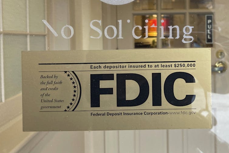An FDIC sign that says 'Each depositor insured to at least $250,000' posted in a window