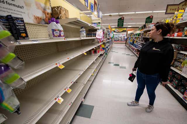 woman looks at empty shelves in grocery store