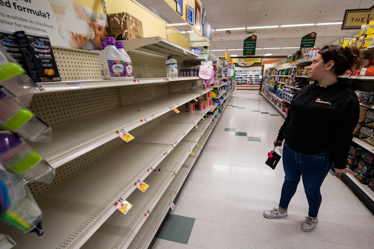 woman looks at empty shelves in grocery store