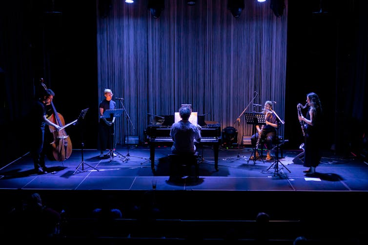 Musicians on a deep blue stage.