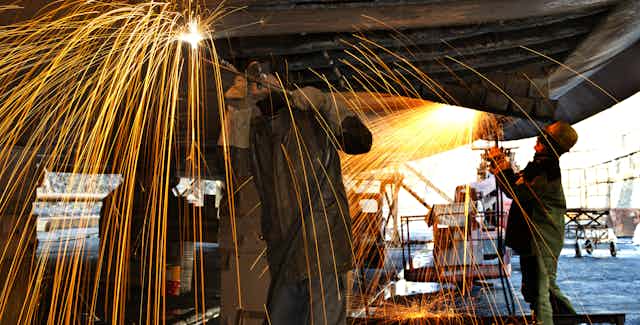 Welders working on a ship in drydock.