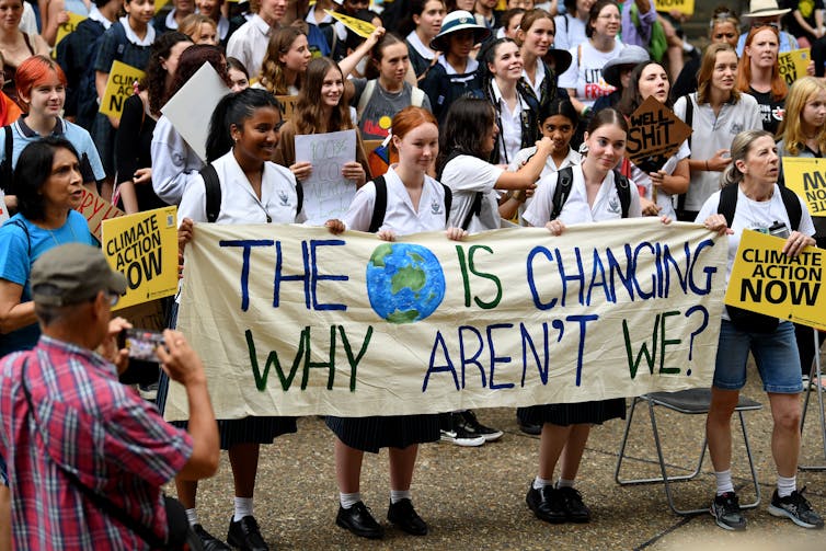 Protesters hold a banner that reads 'The planet is changing, why aren't we?' during a Global Climate Strike protest at Sydney Town Hall, on Friday, March 3, 2023.