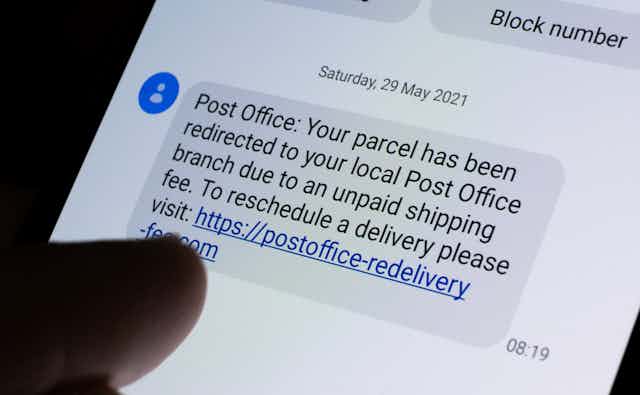 A mobile screen shows a scam post office text message 