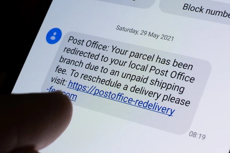 A mobile screen shows a scam post office text message