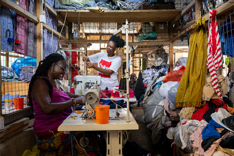 Two women sewing dresses in a shop