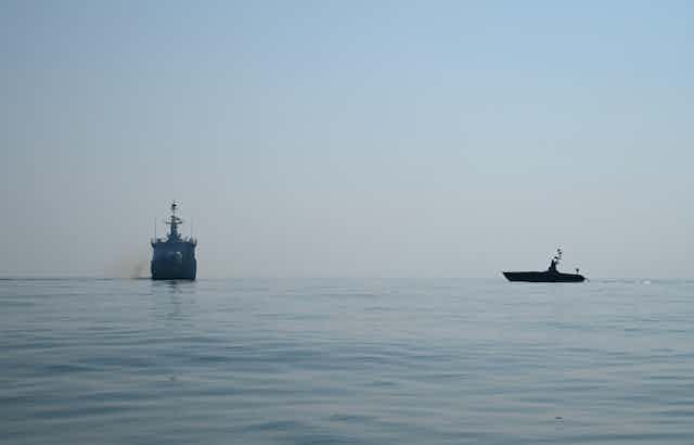 An unmanned surface vessel approaches a target ship during naval exercises.