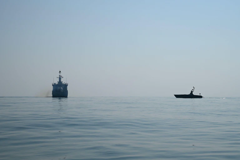 An unmanned surface vessel approaches a target ship during naval exercises.