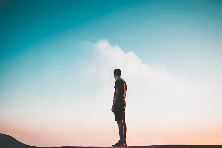 Un homme se tient debout face à un paysage dégagé.