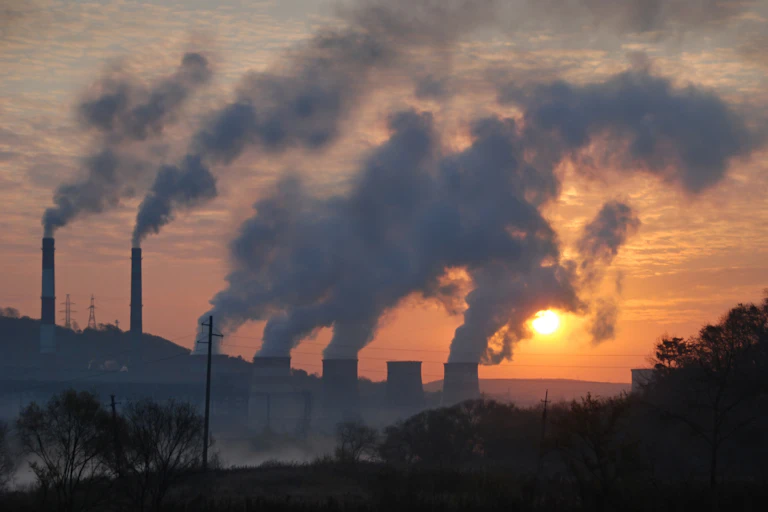 Plumes of smoke going up against a sunset.