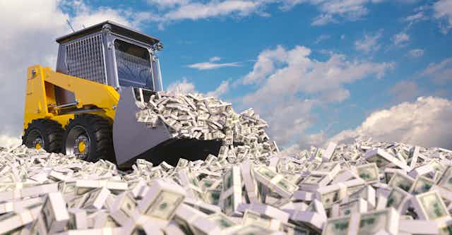 A bulldozer shovels up piles of cash.