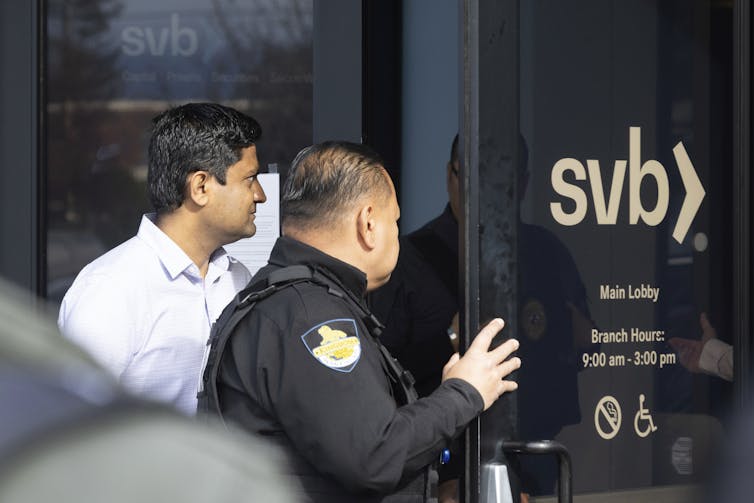 A man and a police officer open the front door to a Silicon Valley Bank buliding
