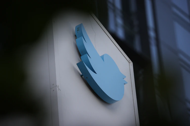 A blue bird emblem isn seen on a wall, surrounded by shadow.