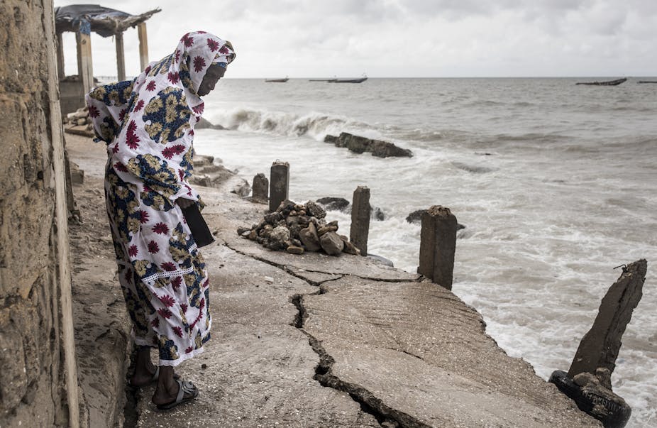 une femme regarde une fissure dans le sol à côté de la mer