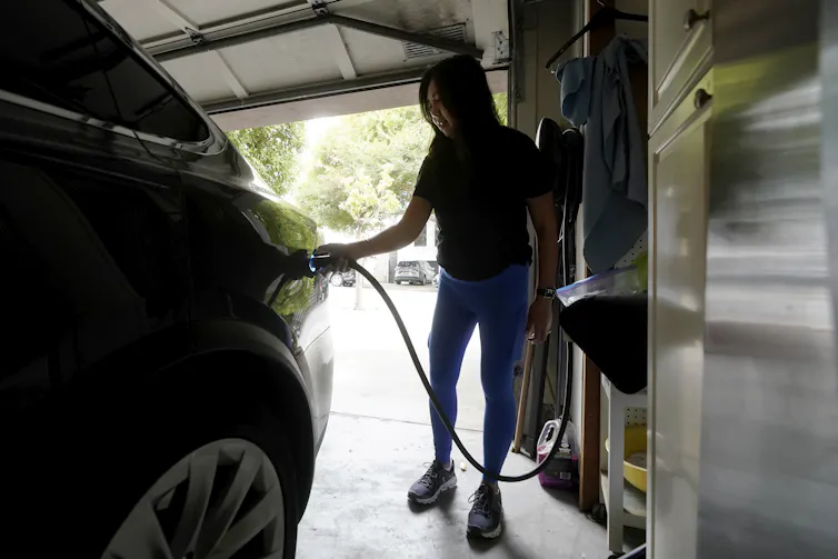 Woman sets up the charging of her car in a home garage