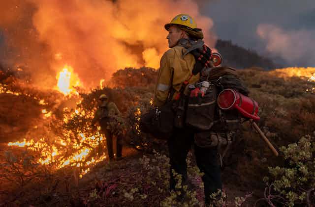 Firefighters loaded with gear walk along the Caldor Fire fire line in 2021.