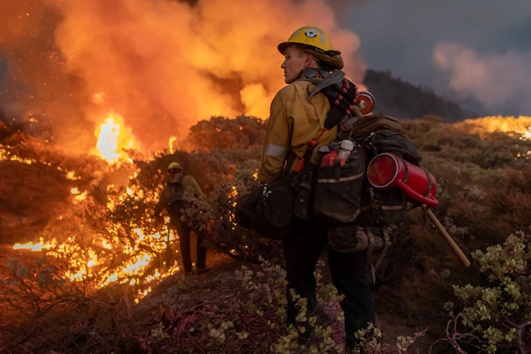 Firefighters loaded with gear walk along the Caldor Fire fire line in 2021.
