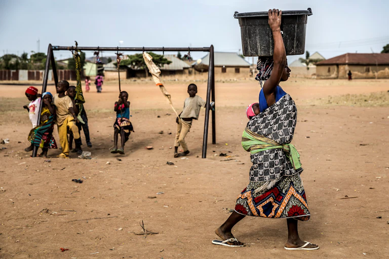 A woman carries a water pot on her head