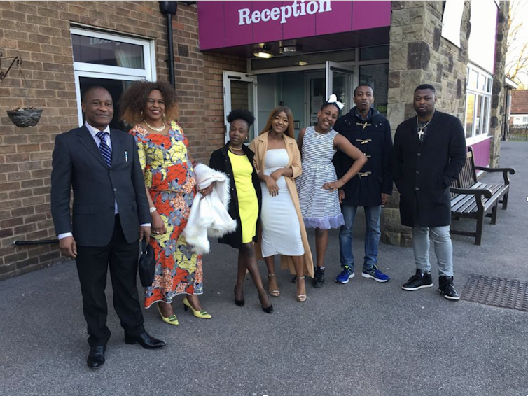 A group of people in smart clothes stand outside a building.