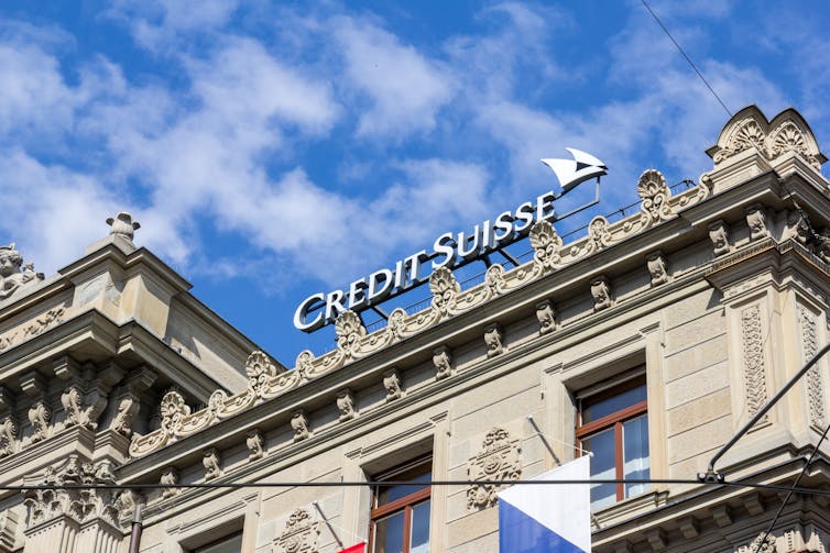 Ornate building with credit suisse sign, blue sky with clouds; Zurich, Switzerland - April 19, 2021. Credit Suisse in the Swiss financial centre of Zurich city.