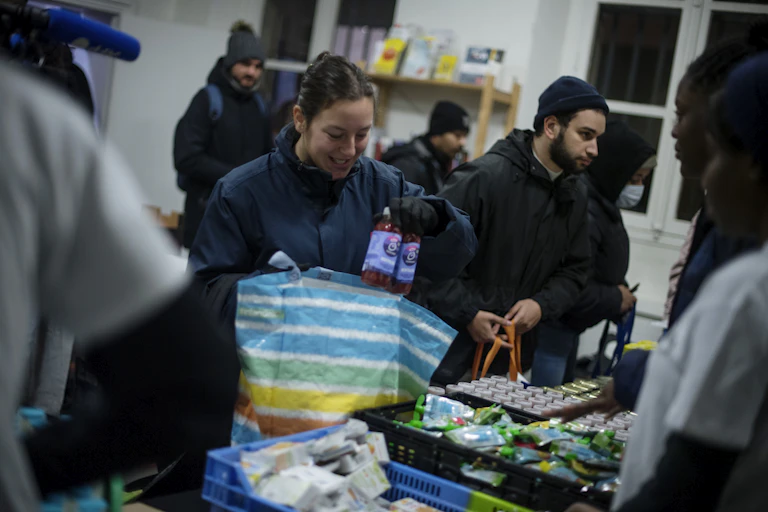 Une étudiante met dans son sac des produits distribués par une banque alimentaire.