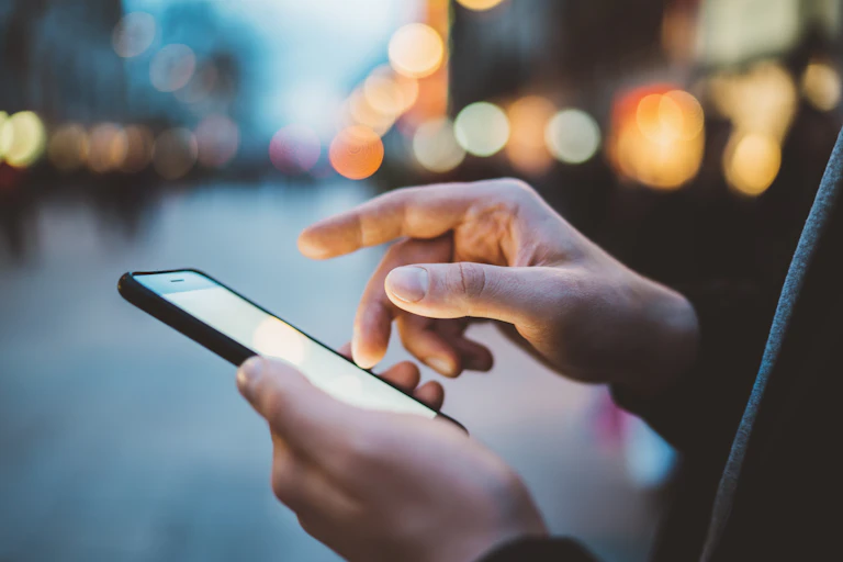Close up of a man's hands as he uses a phone in the street.