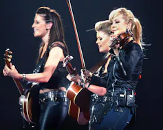Three women perform on a stage.