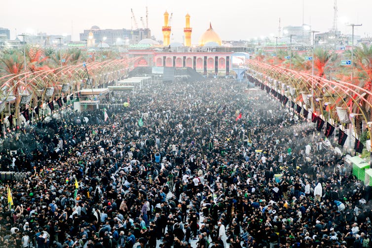 Thousands of people gather in front of a shrine