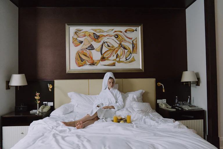 woman sitting on hotel bed in dressing gown.