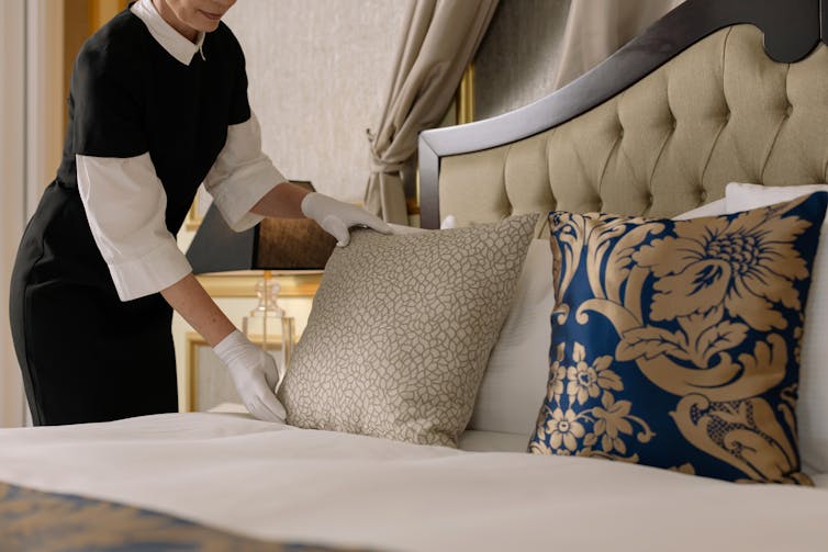 Woman making bed in hoteroom.