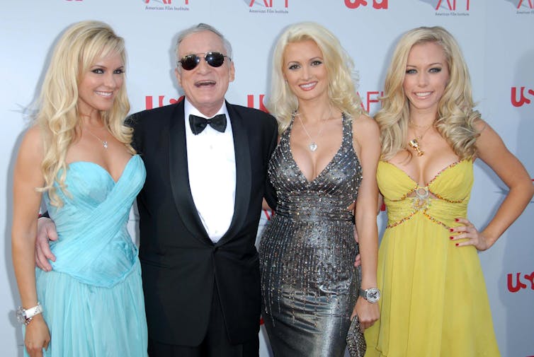 Bridget Marquardt and Hugh Hefner with Holly Madison and Kendra Wilkinson wear glamorous clothing on a red carpet photoshoot.