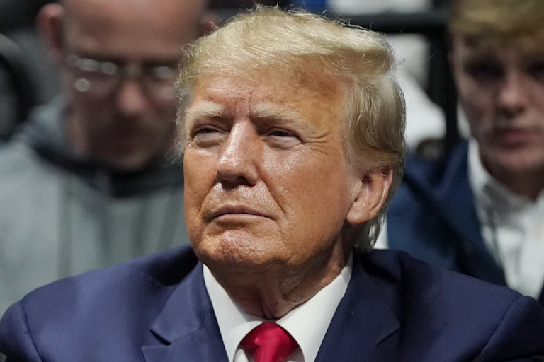 A man with blond hair, red tie, white shirt and blue jacket.